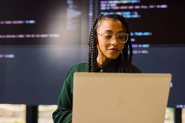 Young software developer analyzing code on a laptop and a large screen